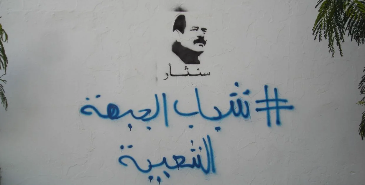 Stencil con el rostro de Choukri Belaid y la inscripción en árabe “Juventudes del Frente Popular” pintada en un muro de Túnez