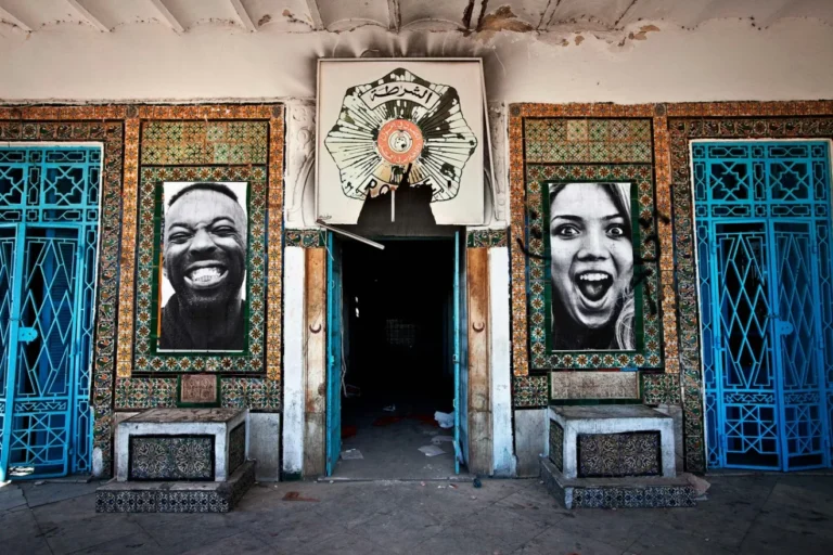 Dos retratos fotográficos en blanco y negro instalados simétricamente en la fachada de un edificio tunecino, proyecto INSIDE-OUT: Autocrazy in Tunisia.