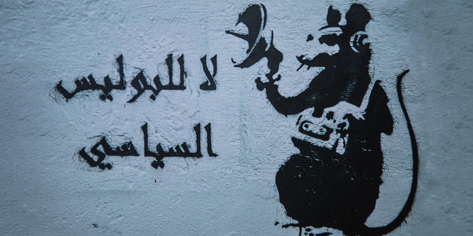 Grafiti del colectivo Ahl al-Kahf con la consigna en árabe «لا للبوليس السياسي» (“No a la policía política”) y una rata con megáfono, Túnez, 2011.